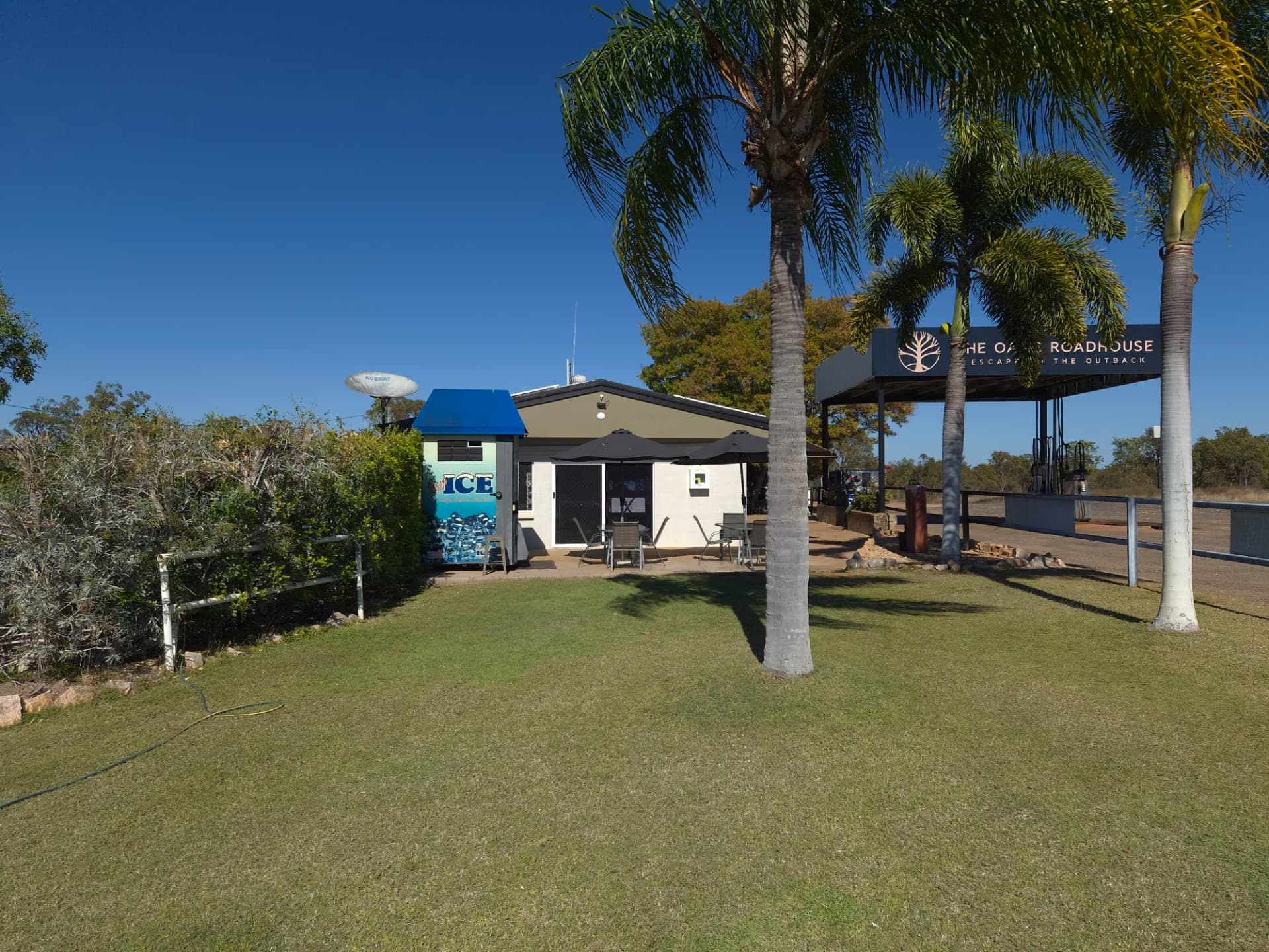 The roadhouse building with palms and fuel canopy